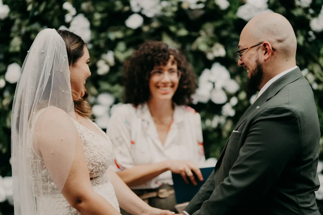 A couple laughing with Charity during an outdoor ceremony