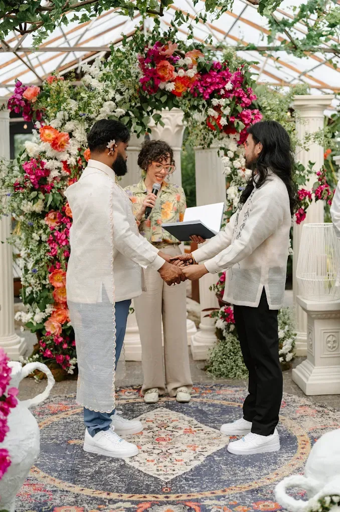 A couple exchanging vows beneath a colourful floral arch